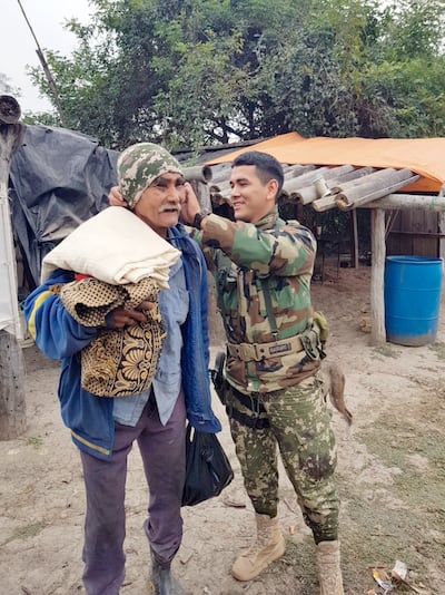 Hace unos meses, unos militares le entregaron prendas de vestir y mantas  a Moro vai. Aquí, uno de ellos le coloca una gorra.