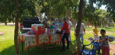 Las personas retirando las comidas de la capilla de la villa San Pedro.
