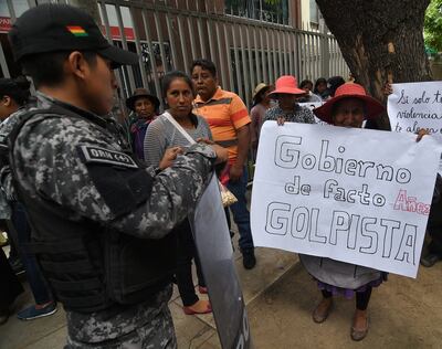 Un grupo de detractores del Gobierno interino de Bolivia muestra este lunes pancartas de denuncia por la actuación militar y policial en operativos en los que murieron civiles por disparos, en Cochabamba (Bolivia).
