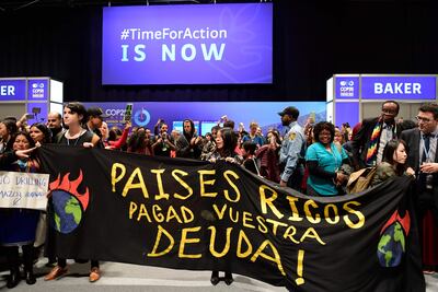 Climate activists unfold a banner reading "Rich Countries pay your debt!" during a protest at the UN Climate Change Conference COP25 at the 'IFEMA - Feria de Madrid' exhibition centre, in Madrid, on December 11, 2019. - Nations are gathered in Spain's capital to finalise the rulebook of the 2015 landmark Paris climate accord, which aims to limit global temperature rises to "well below" two degrees Celsius and to a safer cap of 1.5C if possible. But the consensus-based talks are bogged down in politically charged wrangling over the architecture of carbon markets, timetables for the review of carbon-cutting pledges, and a new fund to help poor countries already reeling from climate impacts. (Photo by CRISTINA QUICLER / AFP)