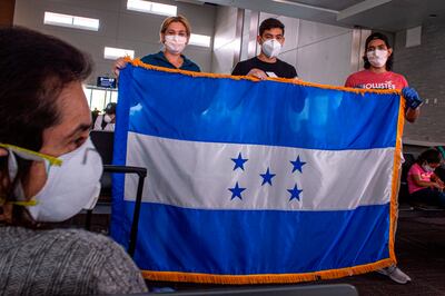 Un grupo de hondureños varados en Estados Unidos por el coronavirus sostienen la bandera nacional ante de subir a un avión este sábado en el Aeropuerto Internacional de Fort Lauderdale, a 40 kilómetros al norte de Miami, Florida (EEUU). Un vuelo especial de la compañía Spirit se llevó este sábado de regreso a su país a 150 hondureños a los que el cierre de fronteras por el COVID-19 sorprendió estando de visita en EE.UU. y quedaron varados, una situación en la que todavía están muchos otros que esperan una nueva oportunidad para viajar.