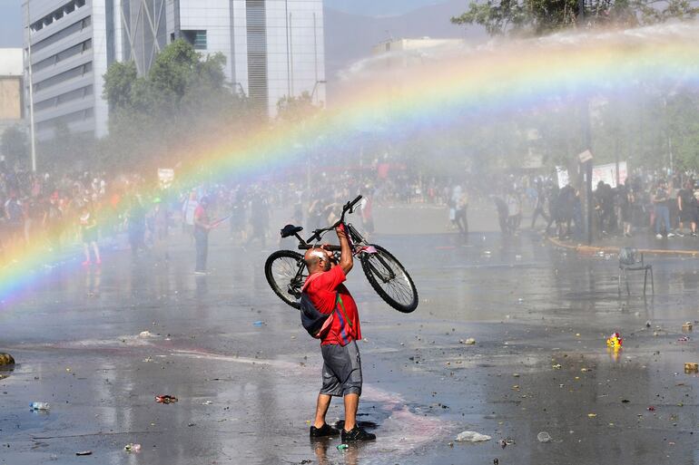 Un manifestante levanta su bicicleta durante un choque con la policía antidisturbios en las calles de Santiago.