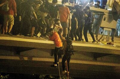 Estudiantes universitarios bajan a través de cuerdas a la calle desde el predio de su universidad, en Hong Kong, para escapar de las fuerzas de seguridad, que amenazaron con utilizar “balas reales” contra los manifestantes.