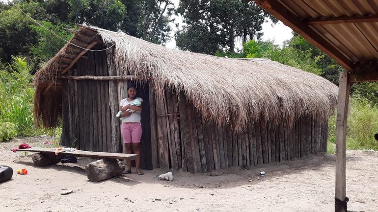La mujer indígena con su pequeño hijo frente a la choza en que viven.