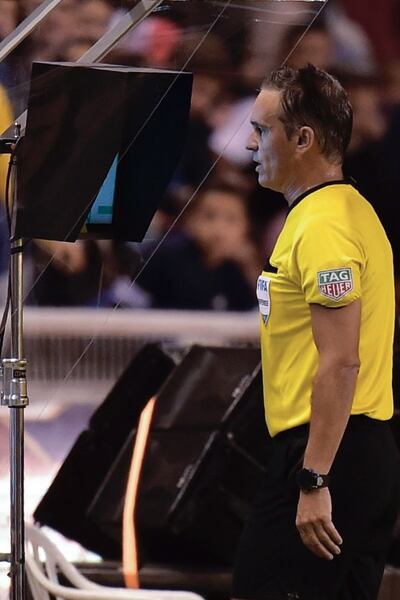 Patricio Loustau mirando el monitor del VAR en el partido entre Liga y Olimpia que se jugó en Ecuador.