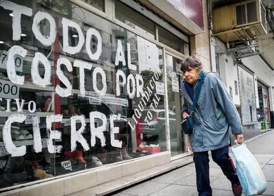 Una mujer pasa frente a una vitrina que anuncia su liquidación por cierre. Fue el jueves en Buenos Aires.