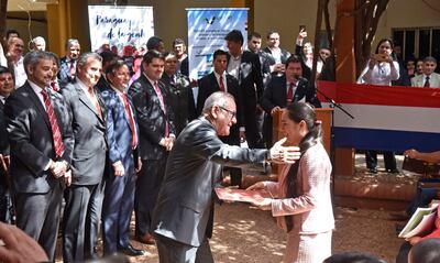 El presidente del Indert, Horacio Torres, entrega el título de propiedad a una beneficiaria, durante el acto realizado  ayer. El presidente de la República, Mario Abdo Benítez (i), también participó.