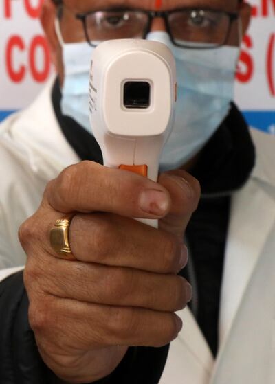 Un miembro del personal médico de la India verifica la temperatura de los pasajeros como medida de precaución contra el coronavirus en una estación de ferrocarril en Jammu, India