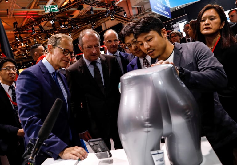 Un expositor explica el sistema que predice cuando una persona debe ir a orinar, al ministro japonés de Economía, Comercio e Industria Yoshihiro Seki, el intendente de  Berlin Michael Mueller y otros funcionarios. 