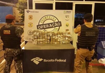 Los agentes de la Fuerza Nacional custodian los 160 paquetes de marihuana prensada incautados del automóvil.
