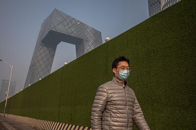 Un hombre con tapabocas camina junto a una obra de construcción en Pekín, China.