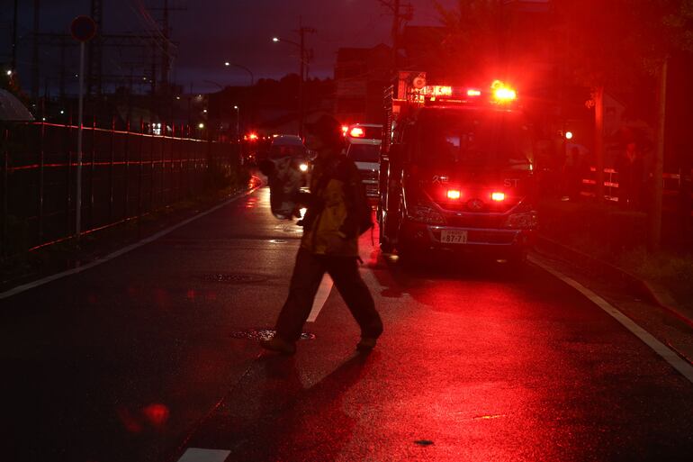 Un periodista camina frente a un coche bomba, frente al edificio donde ocurrió el incendio que supuestamente fue provocado y causó la muerte de más de una veintena de personas. 