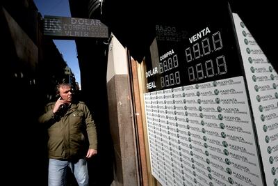 Un transeúnte camina frente a una pantalla que informan el valor de monedas extranjeras, encabezadas por el dólar, respecto al peso argentino este martes, en Buenos Aires (Argentina).