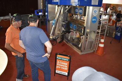Productores observan el funcionamiento del brazo robótico que se encarga de colocar los chupones en las tetillas de la vaca maniquí.