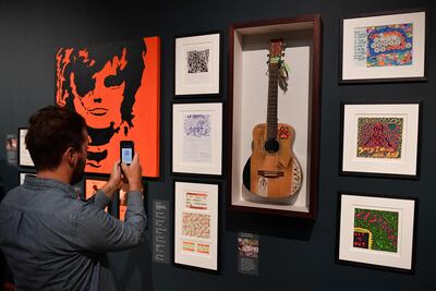 Un visitante a la muestra dedicada a Ed Sheeran fotografía la guitarra usada por el artista británico en sus presentaciones entre 2008-2012.