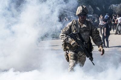 Un solado camina entre el humo de los gases lacrimógenos arrojados por las fuerzas policiales a los manifestantes.