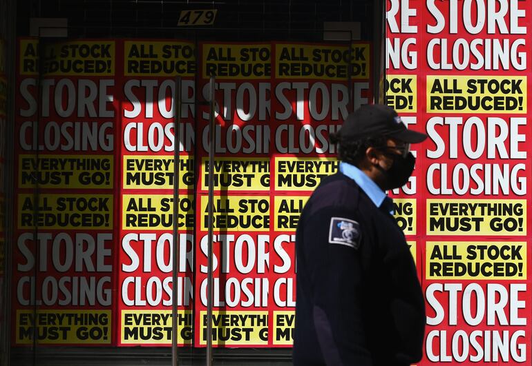 Un hombre camina frente a unos carteles que anuncian el cierre de un local comercial en Brooklyn, Nueva York.