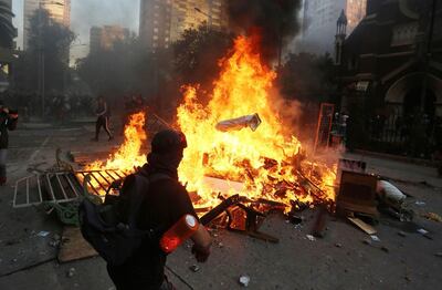 Un manifestante radical lanza al fuego una estatua de la Virgen María en Santiago de Chile.