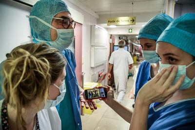 Médicos y enfermeras de la clínica Ambroise Pare en Neuilly-sur-Seine, Francia, miran un video de uno de sus pacientes saliendo de terapia intensiva.
