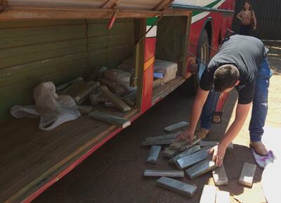 Un agente policial junta los “ladrillos” de marihuana que fueron localizados en el interior de la valijera del ómnibus cateado.