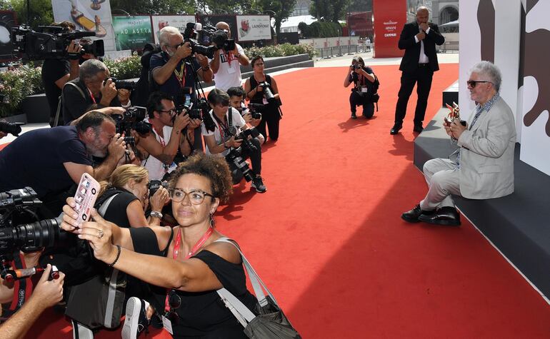 Feliz, Almodóvar frente a las cámaras de televisión y fotógrafos que cubren la edición 76 del Festival de Cine de Venecia.