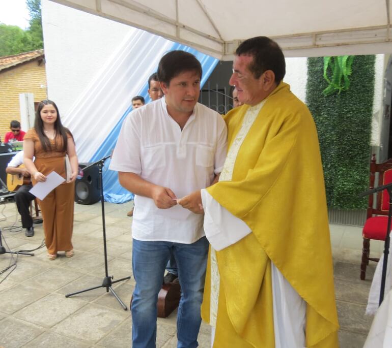 El intendente de Villa Florida Michel Flores durante la entrega del aporte al párroco Mario Núñez.