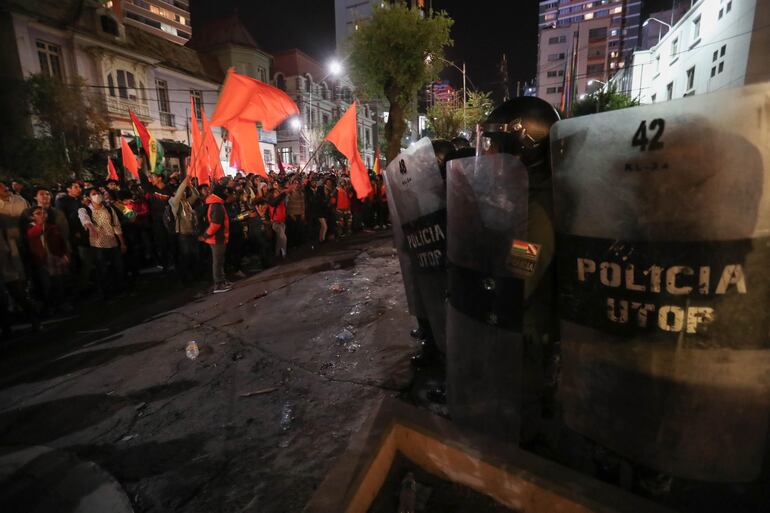 Policias bolivianos vigilan el lugar durante una protesta de simpatizantes de Carlos Mesa y del presidente Evo Morales hoy lunes, durante el computo de actas en La Paz. Adeptos al candidato opositor boliviano Carlos Mesa de Comunidad Ciudadana y al oficialista Movimiento Al Socialismo (MAS) de Evo Morales se enfrentaron en las puertas del hotel donde se realiza el cómputo de actas, ante las sospechas de fraude electoral.