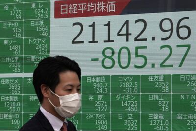 Un transeúnte pasa junto a pantallas que muestran la información de cierre de bolsa del índice Nikkei en Tokio, Japón.