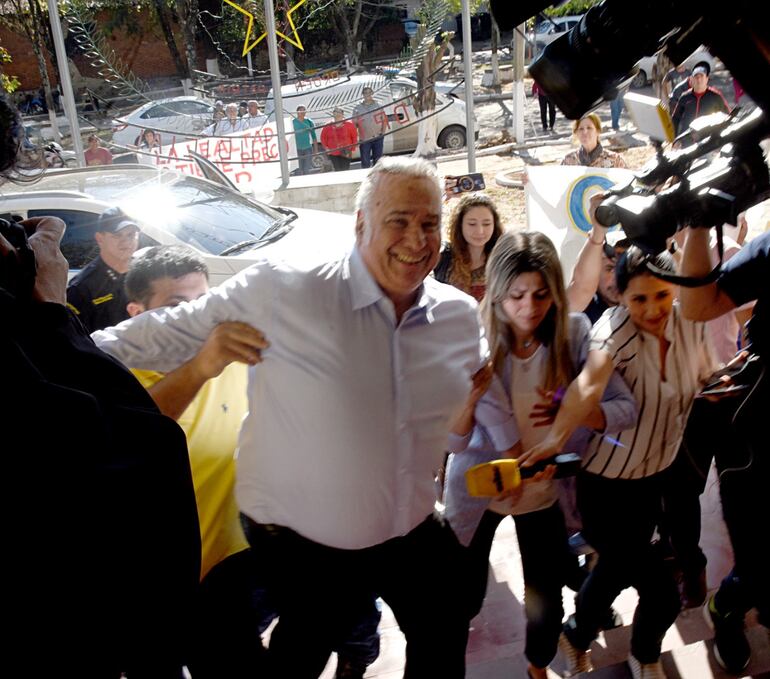 Sonriente, Óscar González Daher sube una escalera flanqueado por sus hijos, minutos antes de ir a la casa donde cumplirá su prisión domiciliaria.