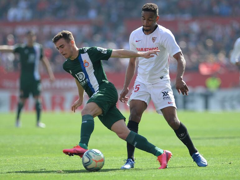Espanyol's Spanish defender Adria Pedrosa (L) vies with Sevilla's Brazilian midfielder Fernando (R)  during the Spanish league football match between Sevilla FC and RCD Espanyol at the Ramon Sanchez Pizjuan stadium in Seville on February 16, 2020. (Photo by CRISTINA QUICLER / AFP)