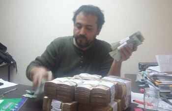 Víctor Ocampos, funcionario de la Municipalidad de Asunción, cuenta fajos de dinero.