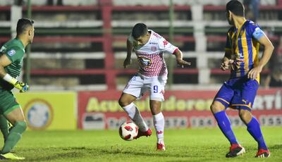 El uruguayo Sebastián Fernández, en medio del arquero Arzamendia y el defensor Joel Benítez, se dispone a sacar el remate que terminará en el segundo gol de San Lorenzo sobre Luqueño.
