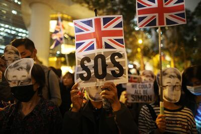 Manifestantes prodemocracia en Hong Kong utilizan máscaras con el rostro de Simon Cheng sosteniendo la bandera británica con un pedido de auxilio.