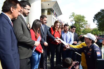 Un par de miembros del Cuerpo de Bomberos voluntarios del Paraguay son recibidos por el presidente de la Cámara de Diputados, Pedro Alliana.
