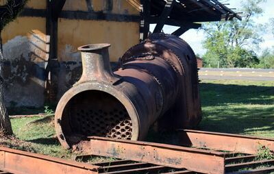 Parte de una locomotora está tirada al costado del viejo edificio. También están una caldera y restos de un tanque de agua.