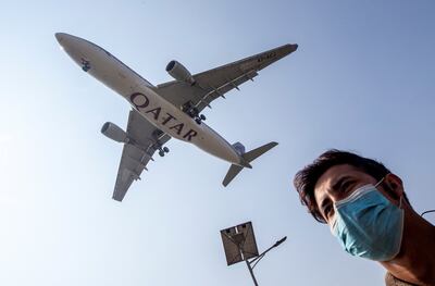 Un hombre camina con una mascarilla mientras un avión de Qatar Airways se acerca para aterrizar en el Aeropuerto Internacional Tribhuvan de Katmandú, Nepal.