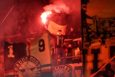 Un hincha del Borussia Dortmund con bengalas en las gradas.