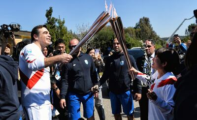 El japonés campeón del maratón olímpico de 2004, Mizuki Noguchi (R) pasa la antorcha al Comisionado Europeo Margaritis Schinas.