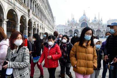 Turistas con máscaras protectoras visitan la Piazza San Marco, en Venecia, el 24 de febrero de 2020 durante el período habitual de las festividades del Carnaval, que los últimos dos días se han cancelado debido a un brote del COVID-19, el nuevo coronavirus.