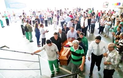 Funcionarios municipales sacan el féretro con los restos de Gervacio Jara del predio comunal. Este falleció por un ACV en medio de la preocupación ya que no cobraba hace meses.