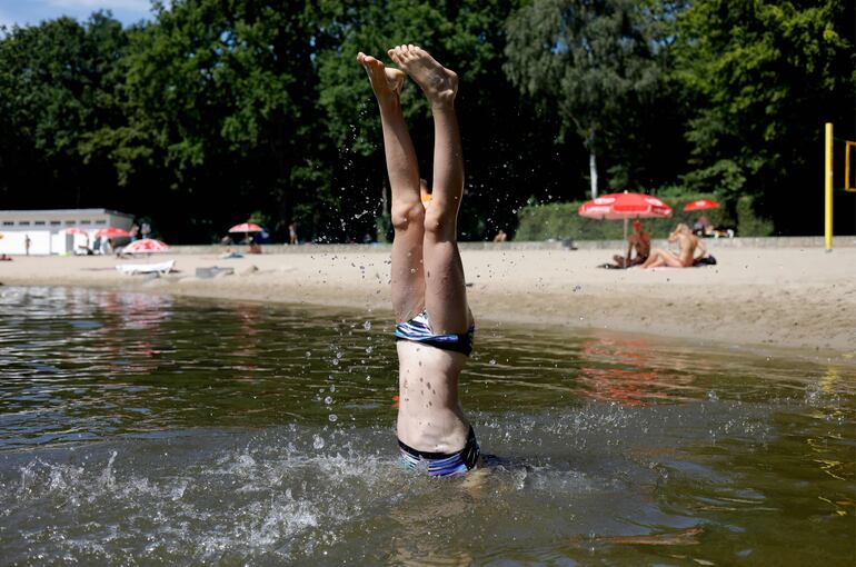 Una chica se para de cabeza en el agua, en una playa cerca de Berlín, Alemania.
