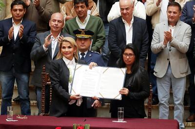 La presidenta interina de Bolivia, Jeanine Áñez (i), sostiene un documento junto a la presidenta del senado Mónica Eva Copa  (del partido MAS, de Evo Morales) durante la promulgación de una ley de urgencia para nuevos comicios.
