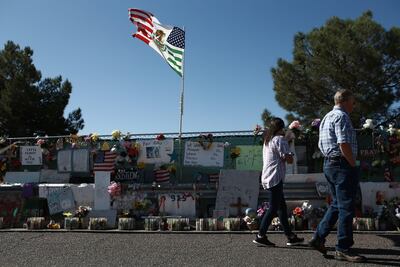 Dos personas caminan frente al memorial instalado a las afueras del centro comercial Walmart de El Paso, donde tuvo lugar el tiroteo.