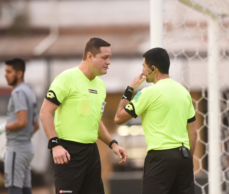 Arnaldo Samaniego, árbitro principal, charla con el juez que se encuentra atrás del arco.