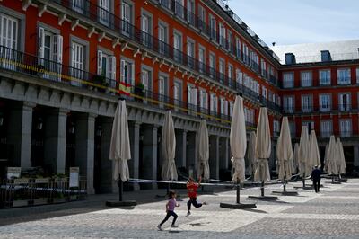 Dos niños juegan al lado de la terraza cerrada de un bar en la Plaza Mayor de Madrid.