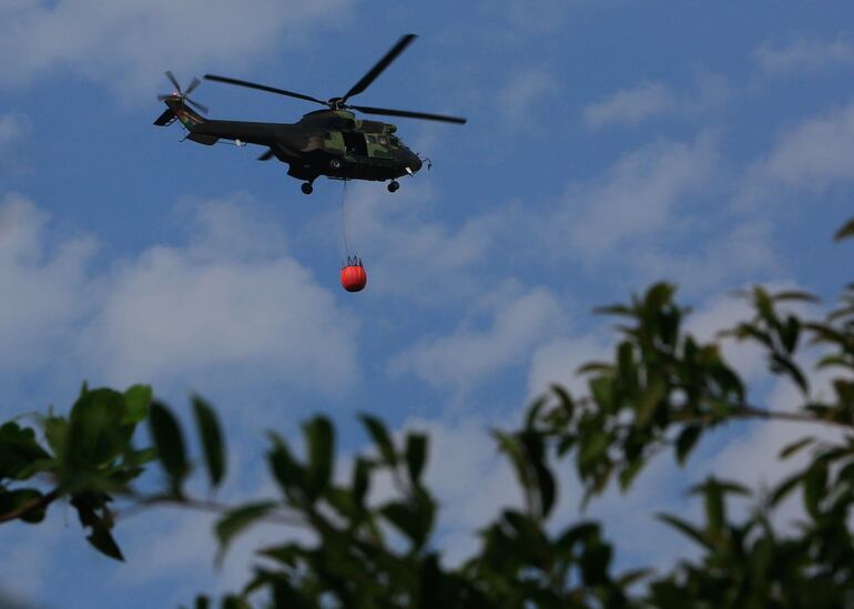 Un helicóptero militar lleva agua para sofocar un punto de incendio, este martes durante una visita del presidente de Bolivia, Evo Morales, en la localidad de Roboré (Bolivia).