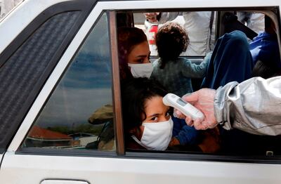 Un miembro de la Media Luna Roja iraní controla a personas con posibles síntomas del coronavirus Covid-19, mientras la policía bloquea la carretera de Teherán a Alborz para verificar todos los autos ordenados por el gobierno iraní, fuera de Teherán, ayer, 26 de marzo.