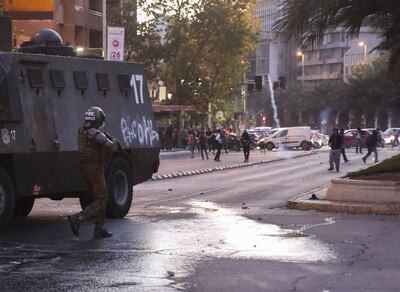 Un carabinero apunta con  escopeta a un manifestante, en el marco de las protestas contra el alza del billete de Metro.