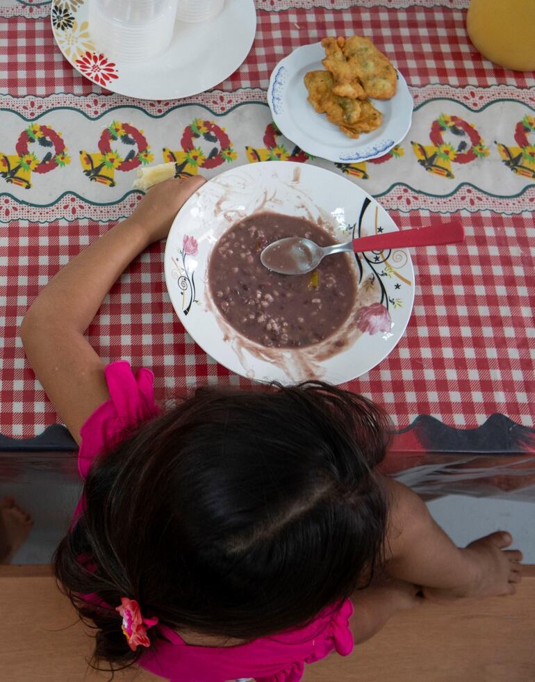 Una niña almuerza el tradicional jopará este martes en un comedor comunitario del Mercado 4 de Asunción (Paraguay).