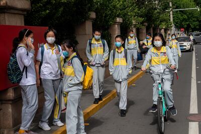 Los estudiantes que usan máscaras faciales en medio de las preocupaciones por el coronavirus COVID-19 abandonan una escuela secundaria en Beijing el 11 de mayo de 2020.